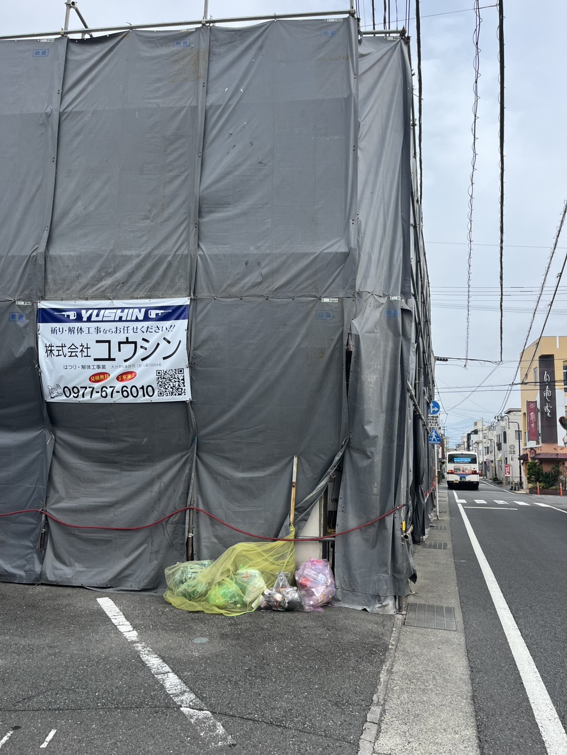 亀川の解体工事現場の外観と株式会社ユウシンの横断幕